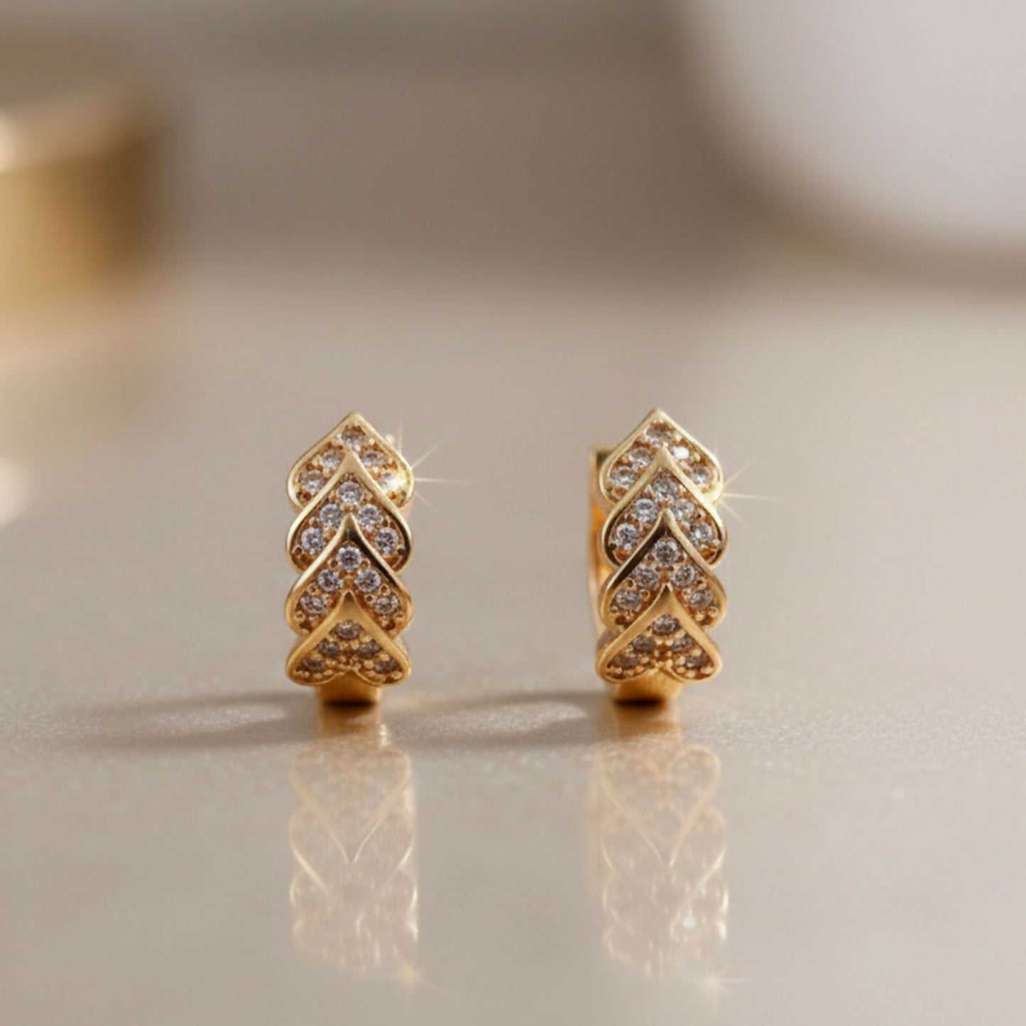Gold finish leaf pattern stud earrings with sparkling stones close-up