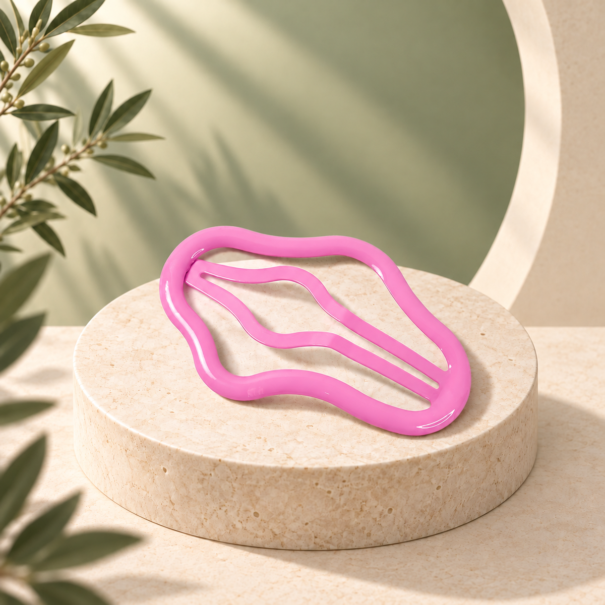 A shiny pink wavy hair clip rests on a light beige marble pedestal, with green foliage in the background.