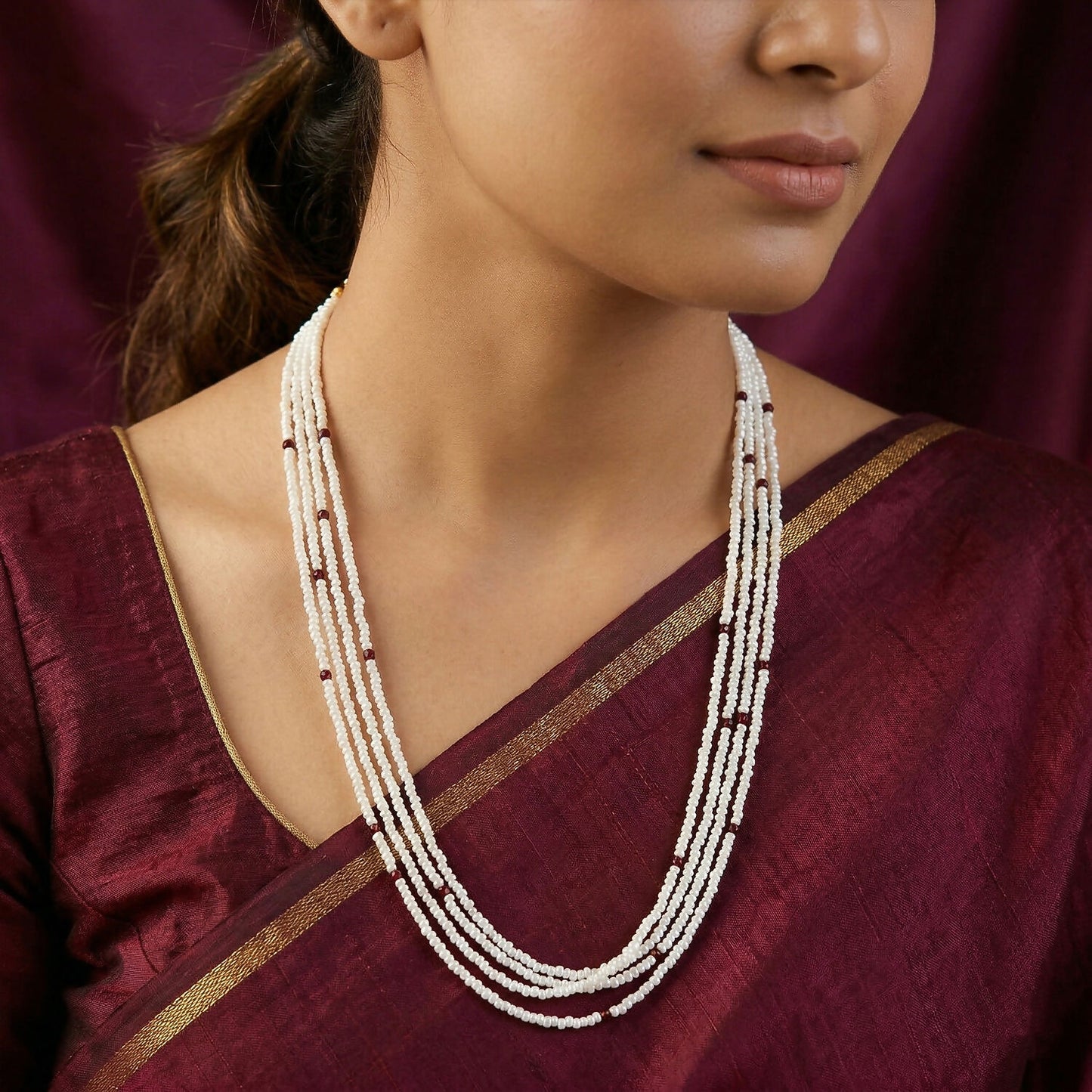 Close-up of handmade white mala necklace beads with maroon details