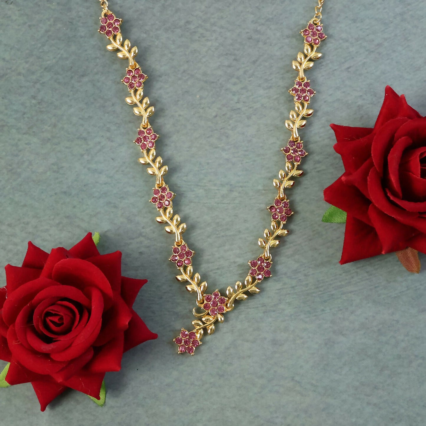 Side view of gold and ruby floral necklace with matching earrings