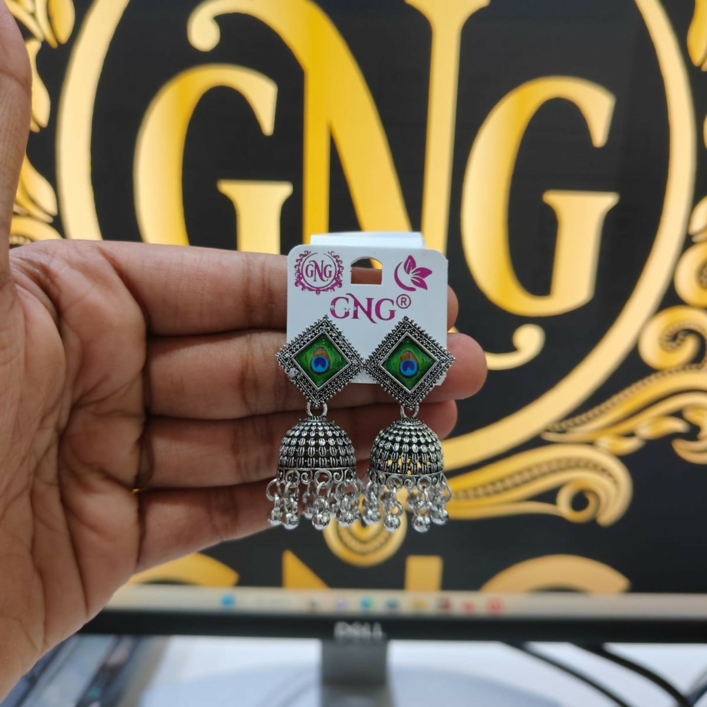 A pair of traditional oxidised jhumka earrings with a clear view of their ethnic design.