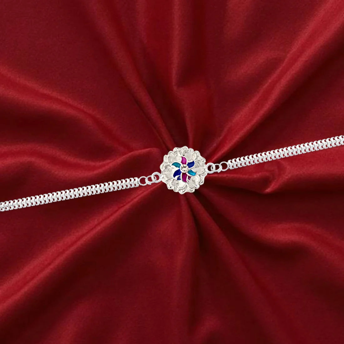 Silver Floral Rakhi displayed on a white surface, highlighting its intricate design.