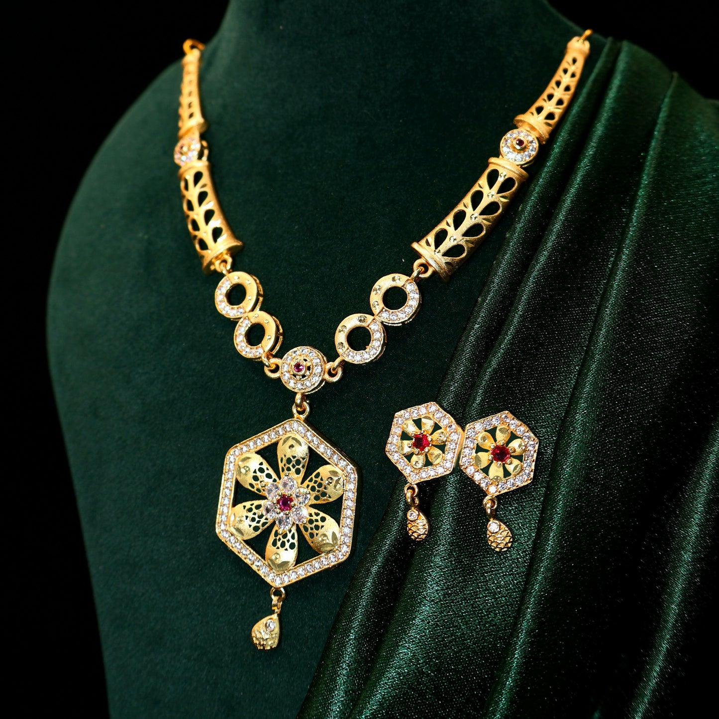 Gold plated hexagon pendant necklace with sparkling stones on white background.