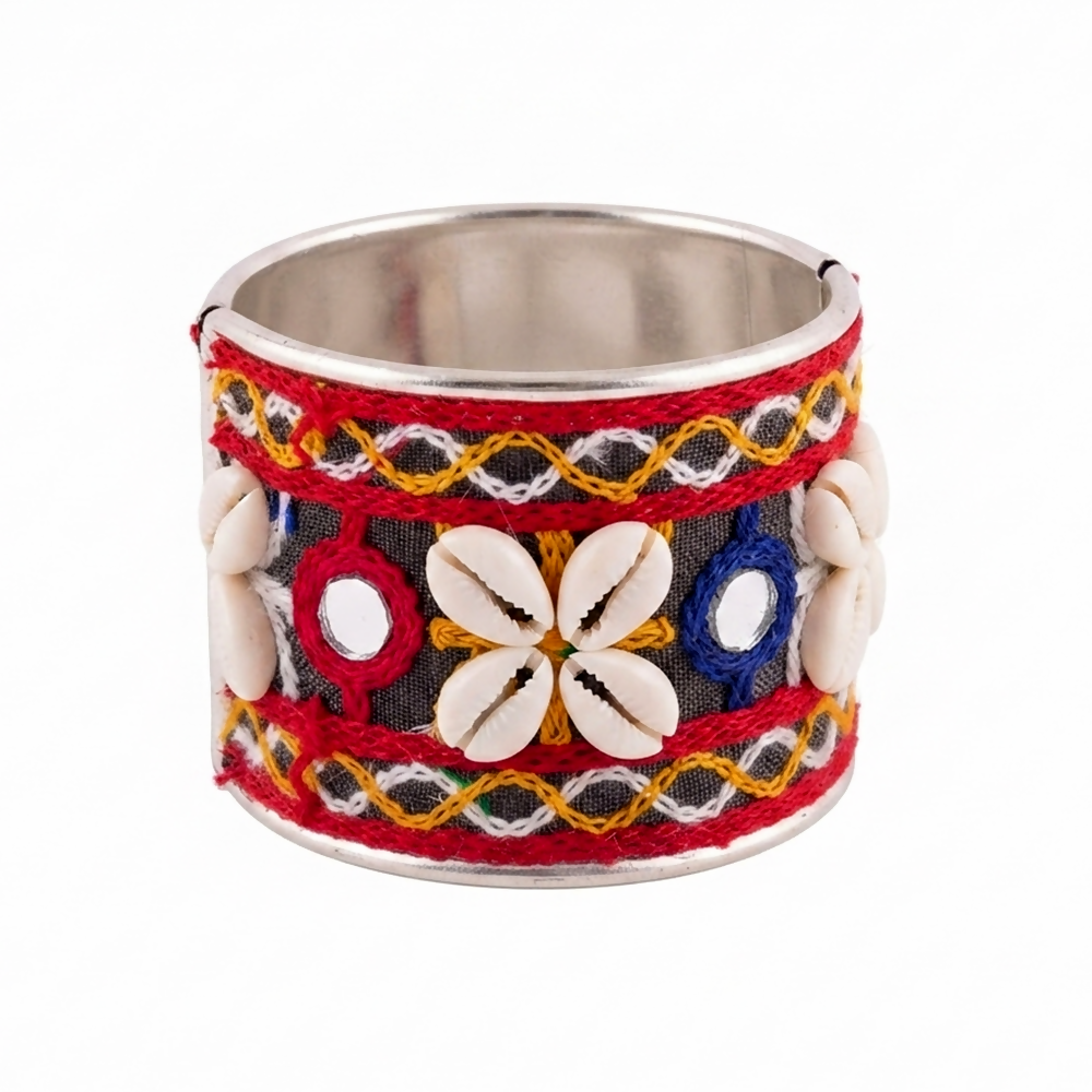 A vibrant silver cuff bracelet features red, yellow, and blue thread work, tiny circular mirrors, and decorative white