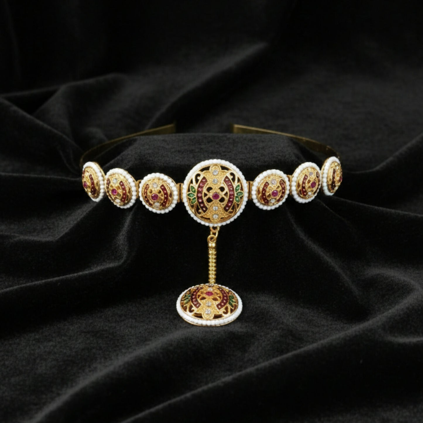 Close-up of vibrant ruby and emerald minakari stones and pearl border on Matha Patti