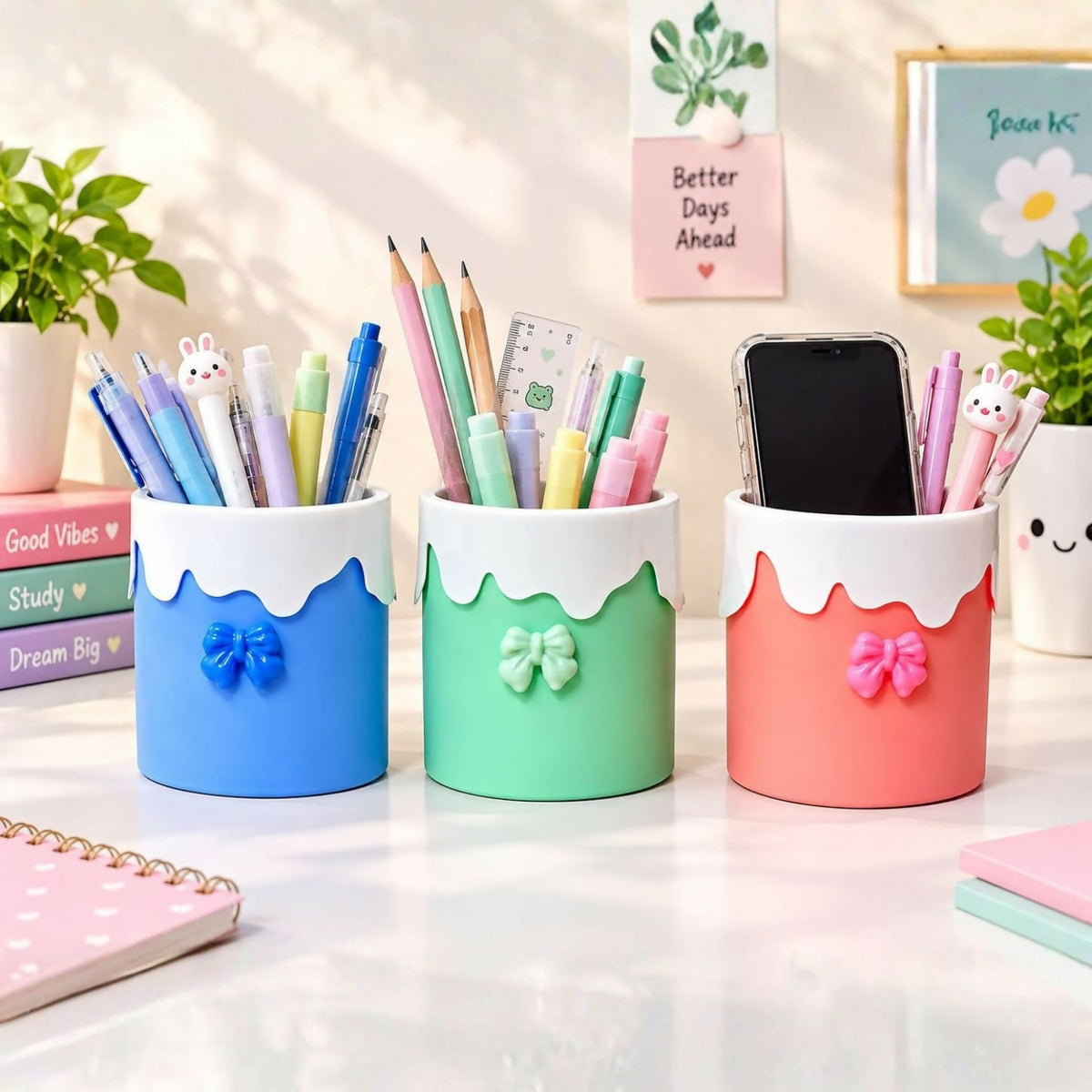 Three pastel organizers on a desk, filled with various pens, pencils, a ruler, and a mobile phone.