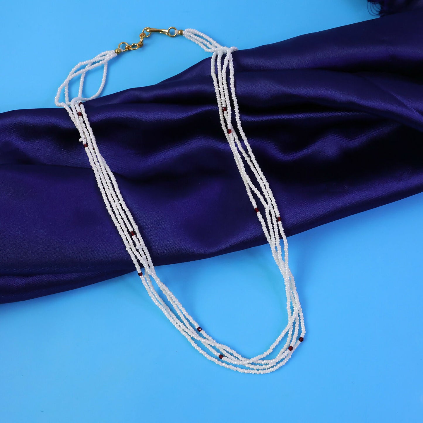 Pearl mala necklace displayed on traditional fabric background