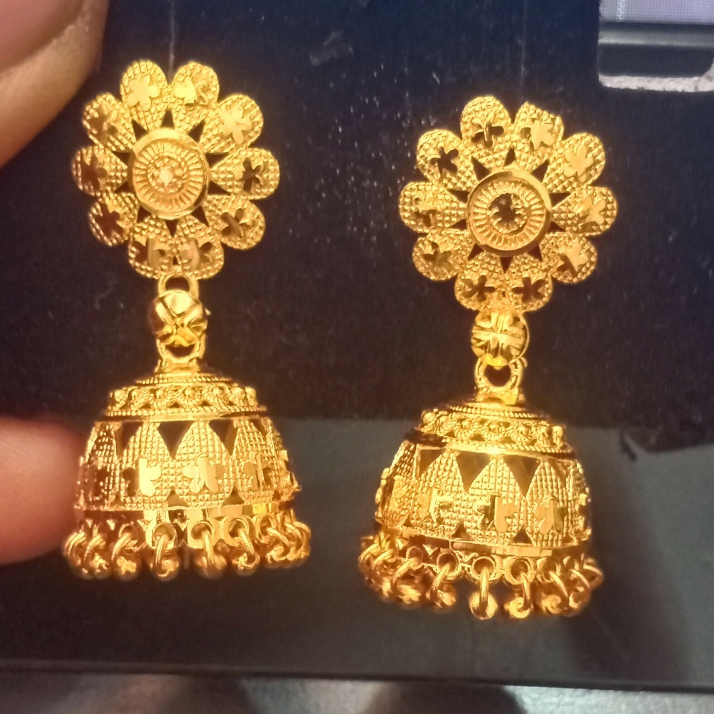 Elegant gold plated jhumka earrings displayed against white background showcasing temple design