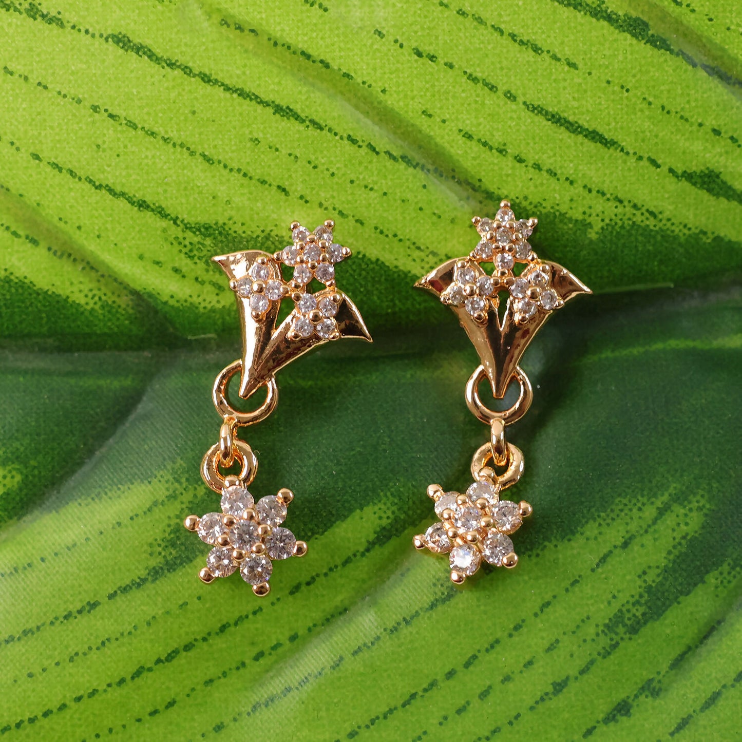 Pair of rose gold star drop earrings with free-swinging floral charm