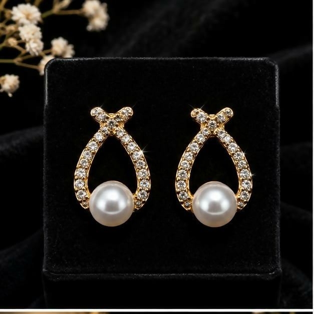 Side view of gold-tone teardrop earring with pearl-look bead and intricate stone work