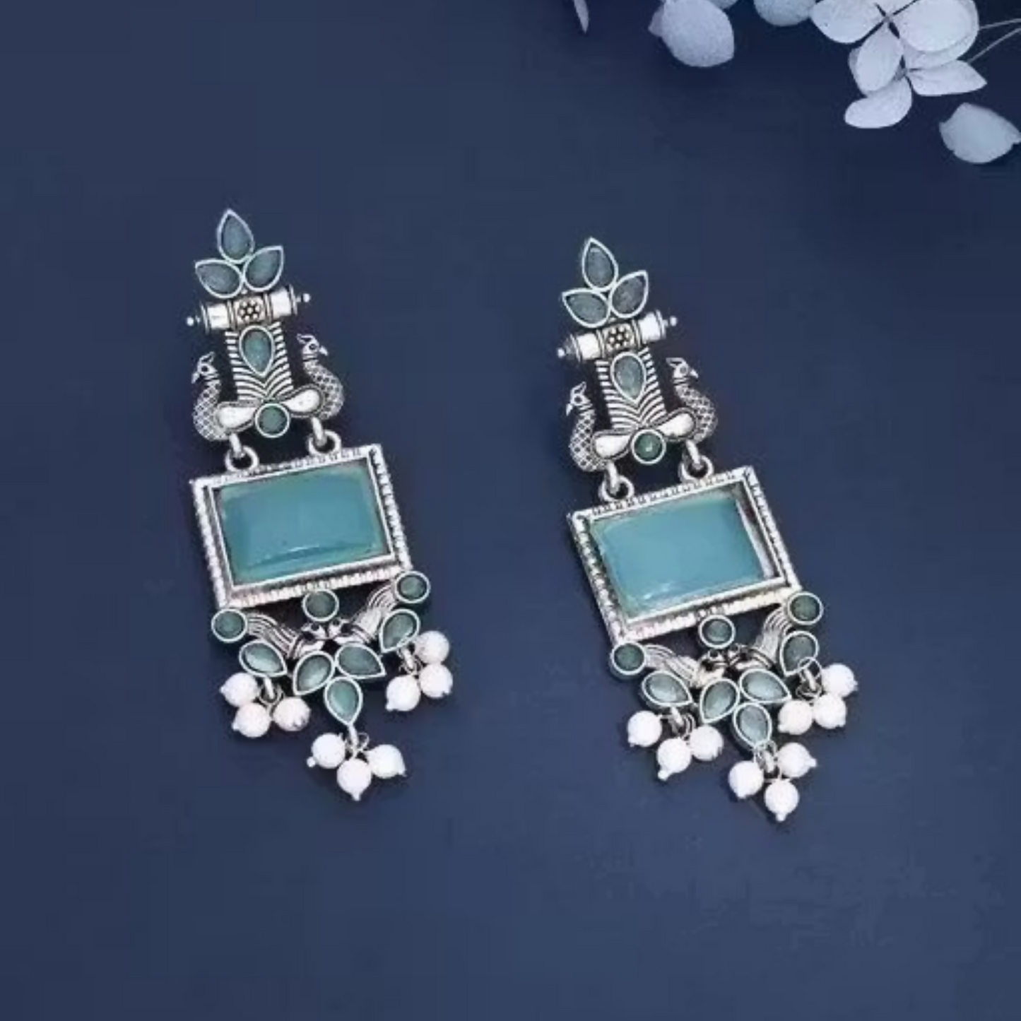 Close-up of oxidized silver blue stone earrings with elegant pearl drops