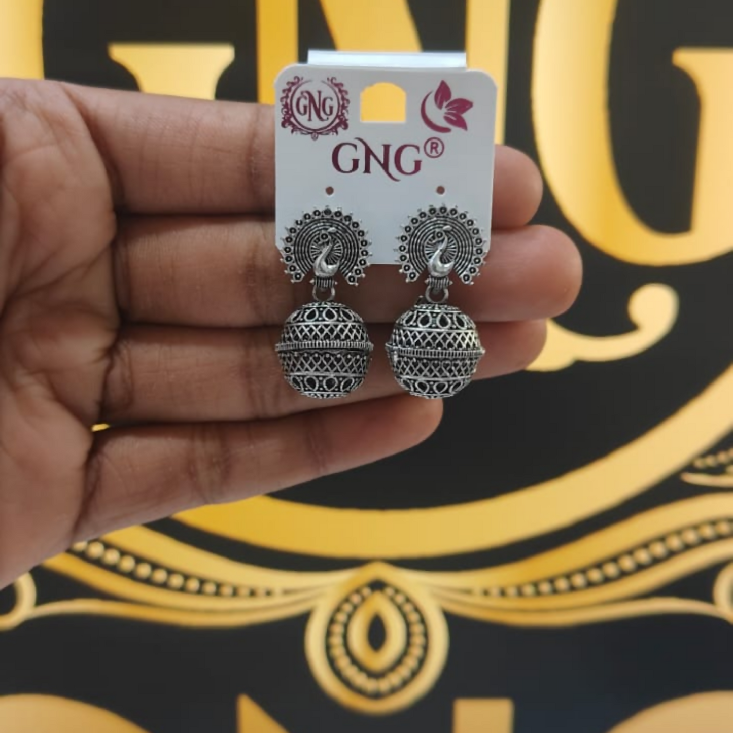 Pair of oxidised peacock jhumka earrings displayed together