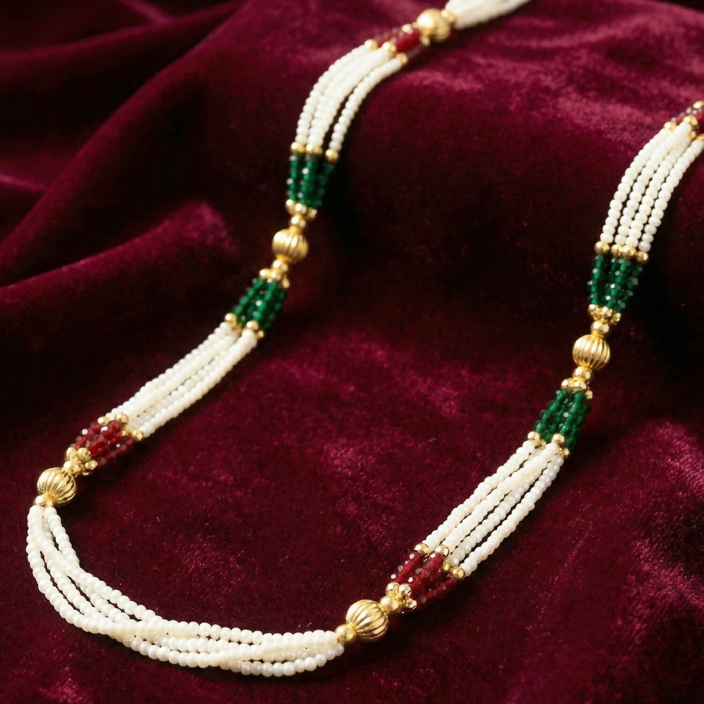 Detailed view of red, green, and gold bead accents on layered pearl strands