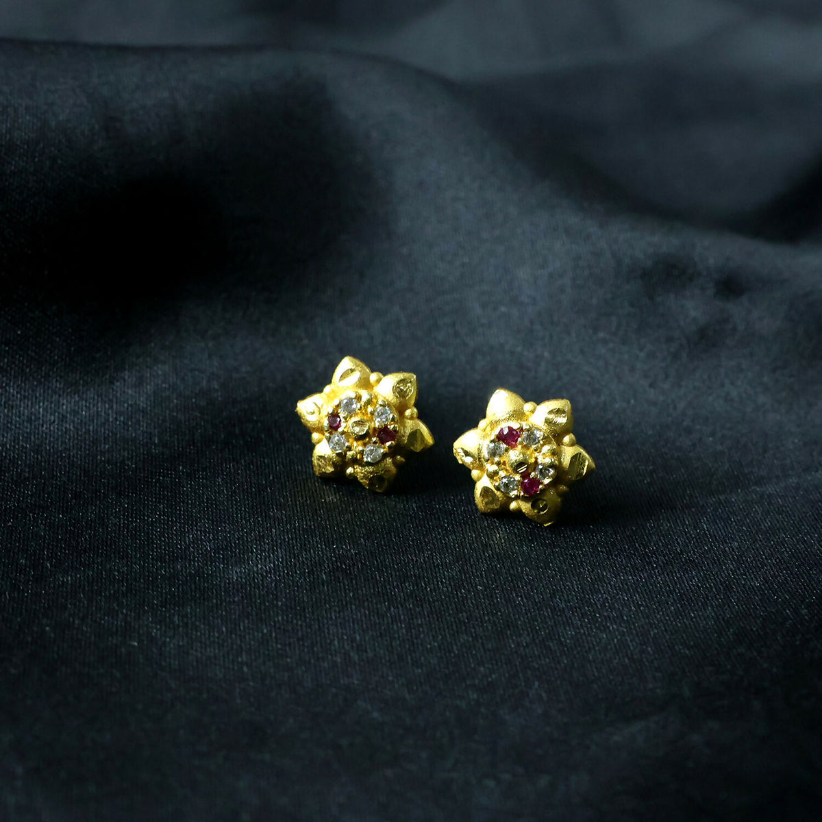 Close-up of intricate floral motif on gold stud earrings with sparkling stones
