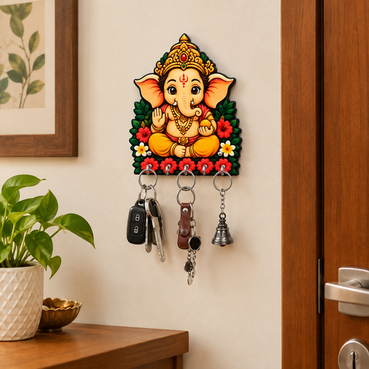A vibrant Ganesh key holder with five hooks, holding keys and a bell, mounted on a light wall next to a wooden door.