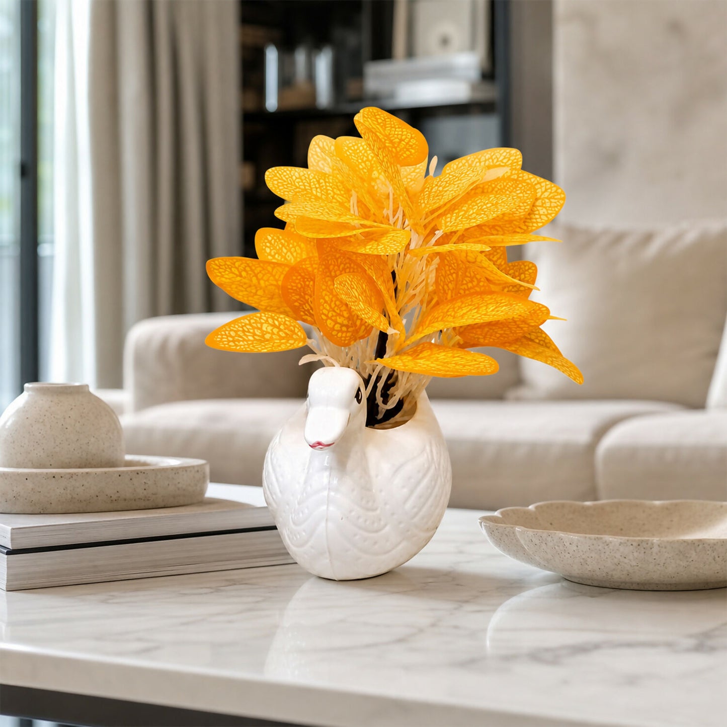 Decorative white ceramic swan vase with orange skeleton leaves on a table