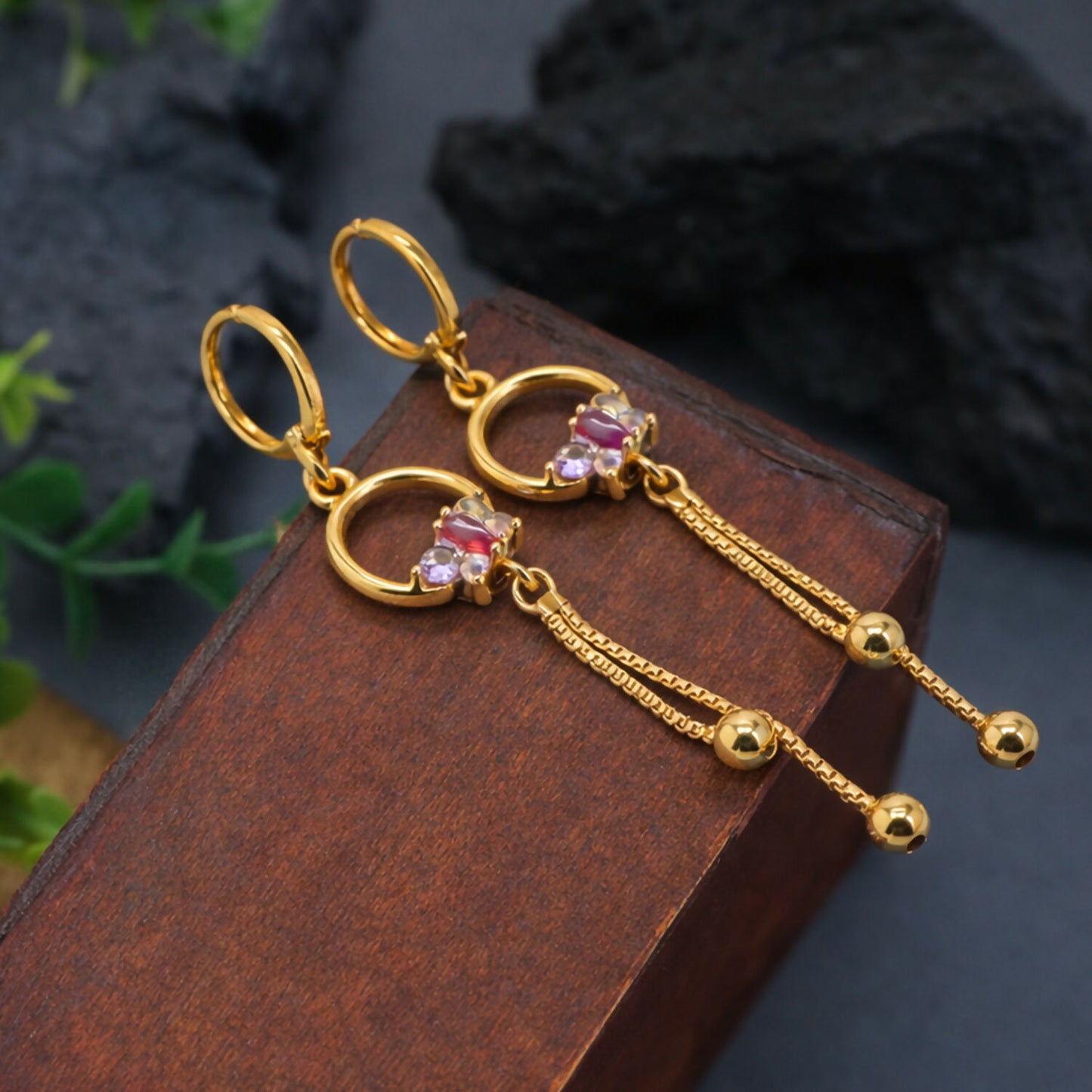 Gold finish circle drop earrings with colorful stone accents and chain tassels on white background