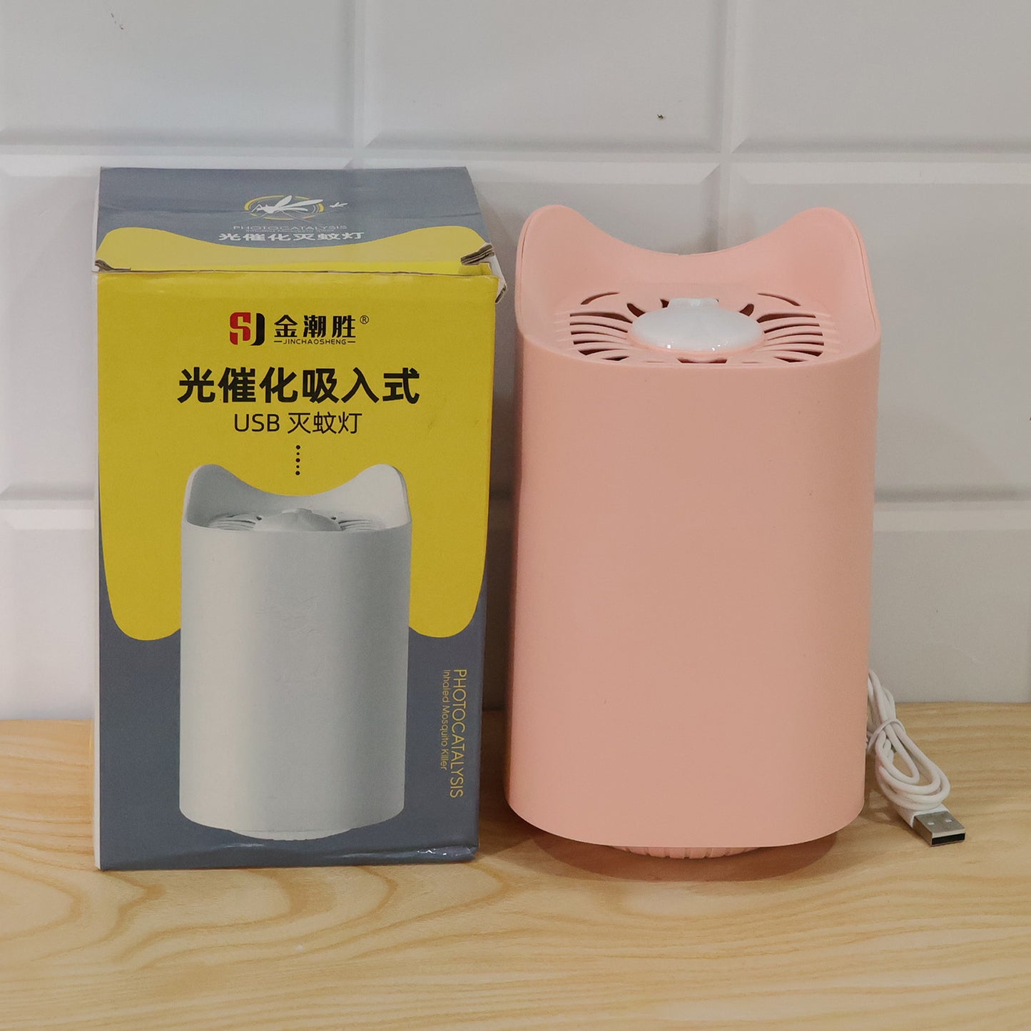 A pink cat-shaped mosquito killer lamp with a USB cable sits next to its product box, which features a white version of the