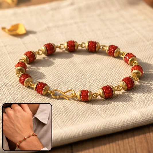 A red rudraksha and gold-plated cap beads bracelet with a hook clasp rests on a light fabric, with a small inset of a person