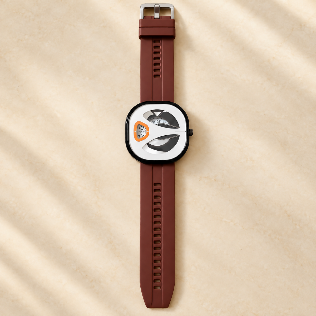 Top-down view of a brown watch with a silicone strap and silver buckle, centered on a light beige surface with shadow