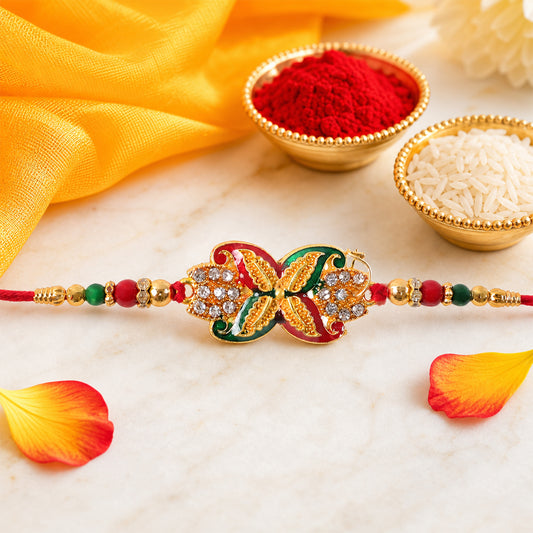 A red thread bracelet with a golden, red, and green flower motif, adorned with clear stones, rests on a marble surface with