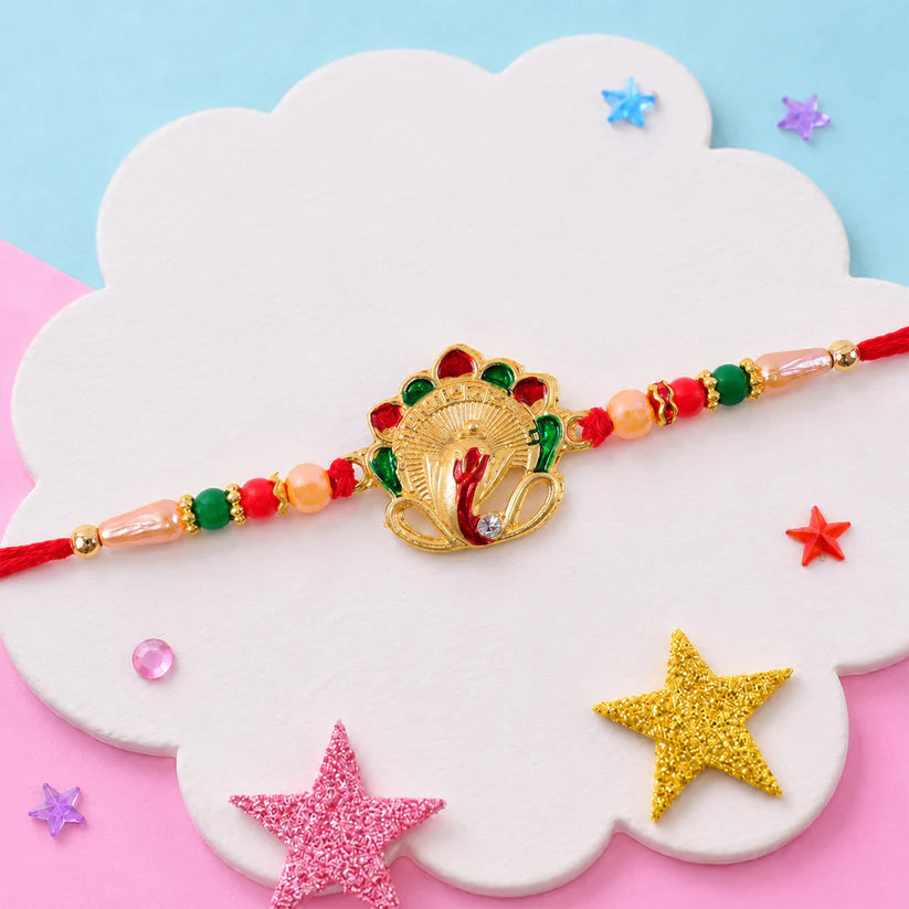Golden enamel Ganesha rakhi with pearl and multicolor beaded thread for Raksha Bandhan.