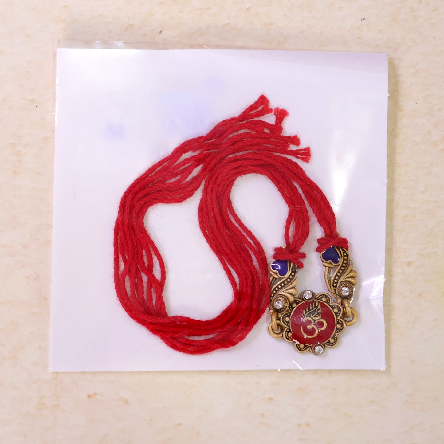 Traditional Rakhi showcasing Om Medallion, red stone accents and chain look for Gift
