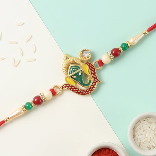 A gold-toned Ganesha charm with green, yellow, and red enamel, flanked by red, green, and cream beads on a red thread.