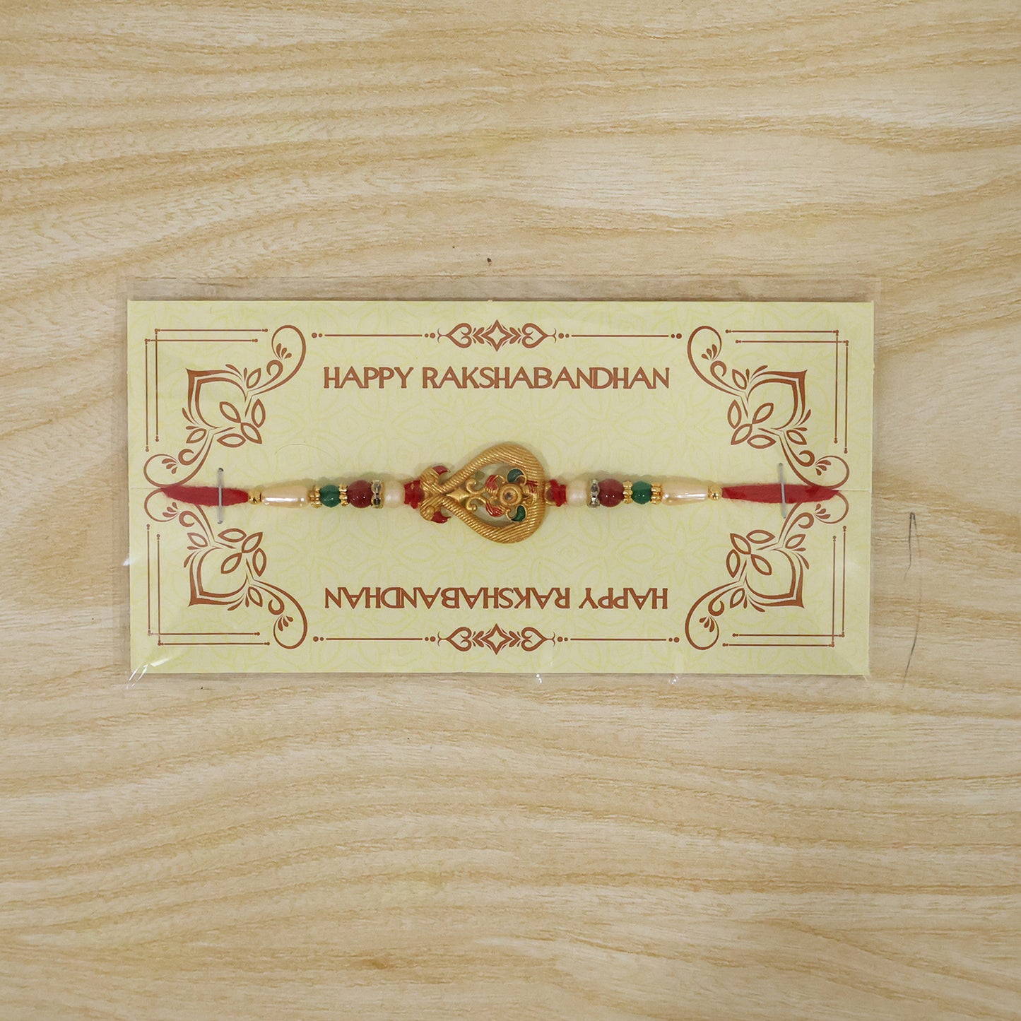A red thread bracelet with a gold-colored, intricate charm and colorful beads, displayed on a