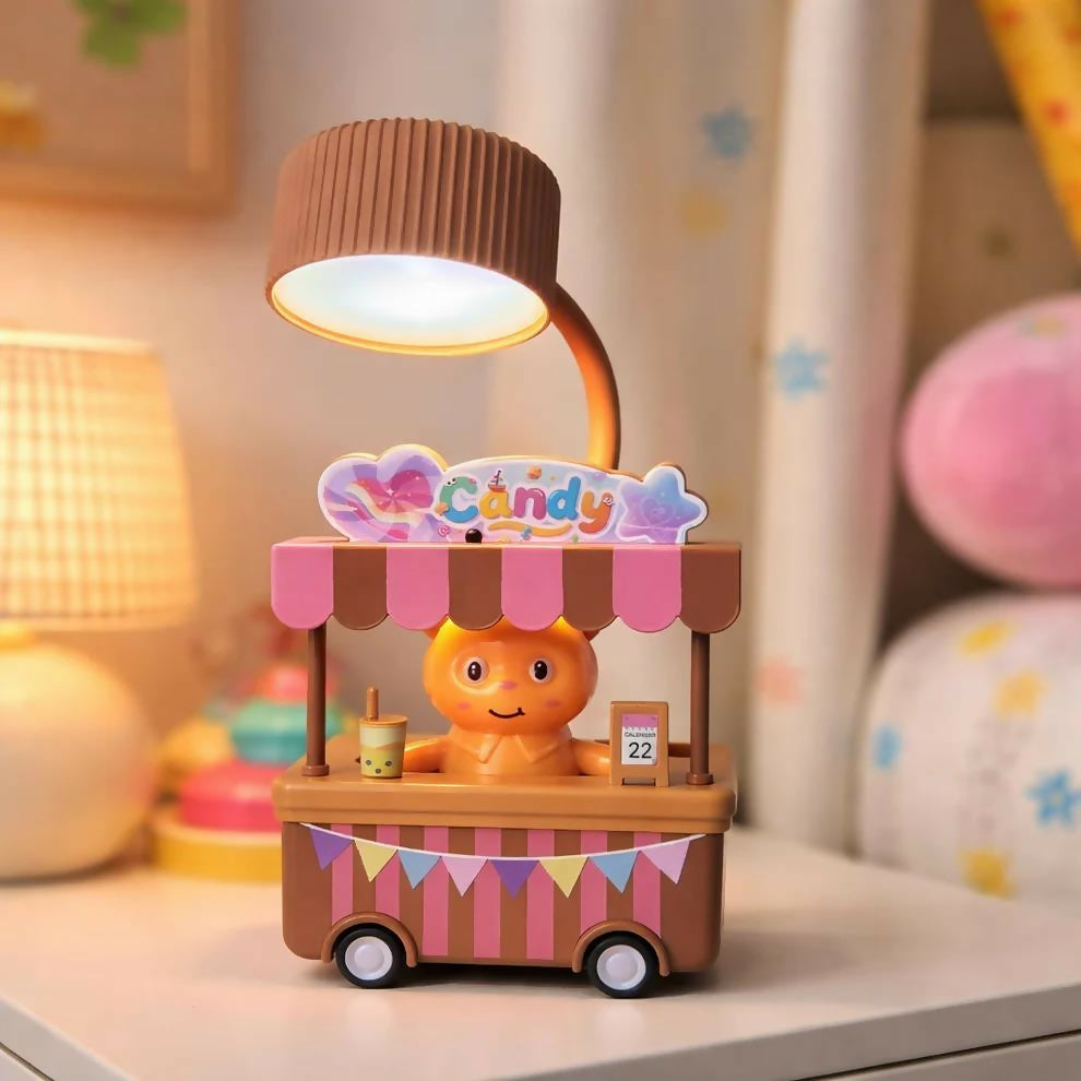 A brown and pink candy cart desk lamp with a glowing light, on a white nightstand with a blurred background.