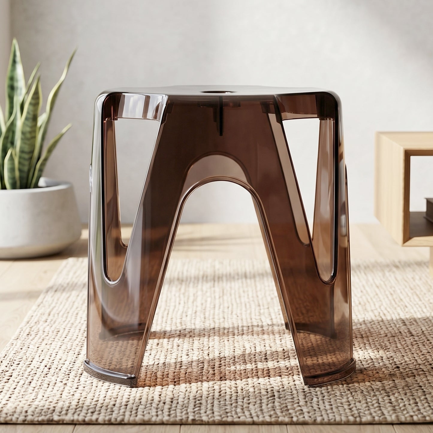 A transparent plastic stool used as a stylish side table next to a sofa.