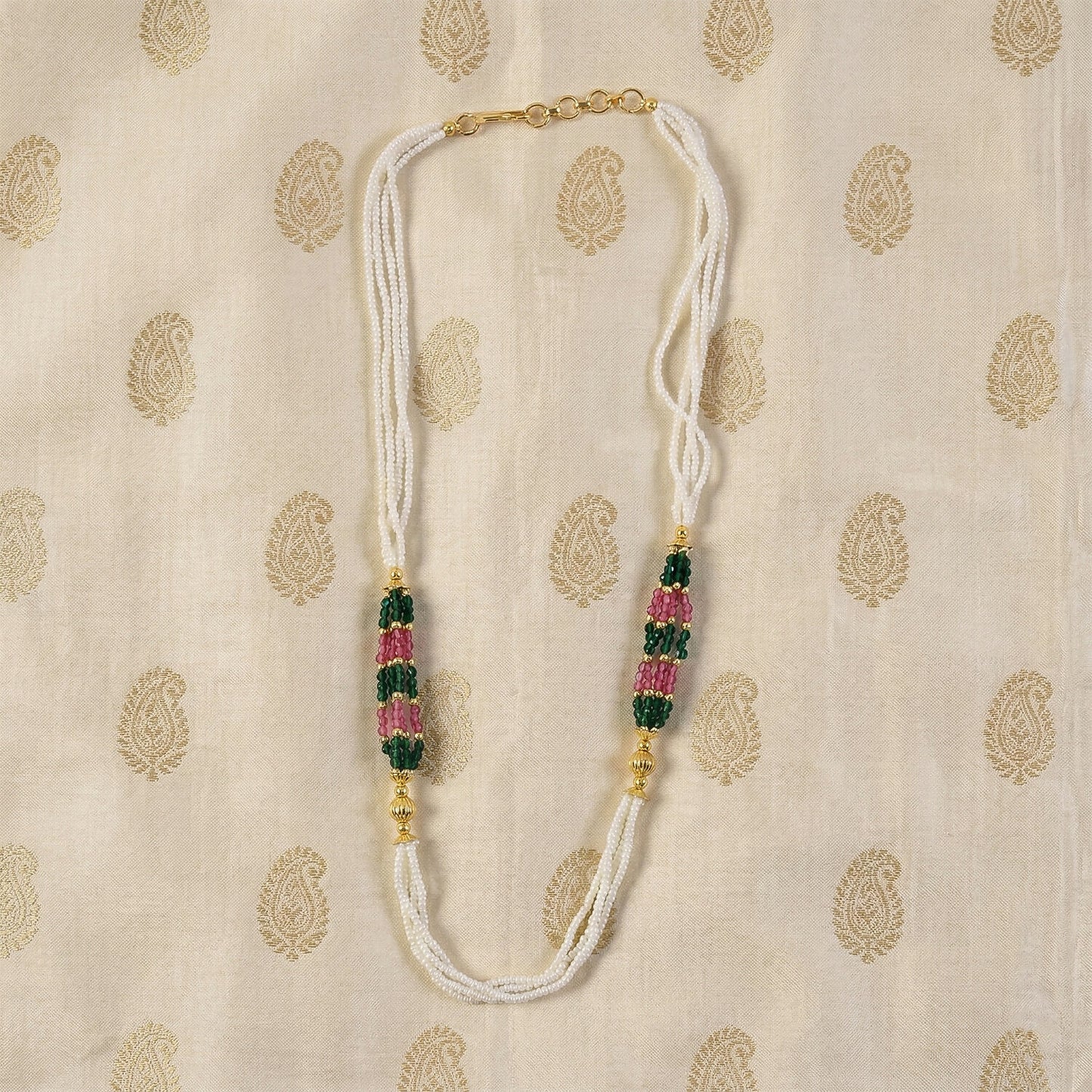 Close-up of green and pink bead details on white mala necklace