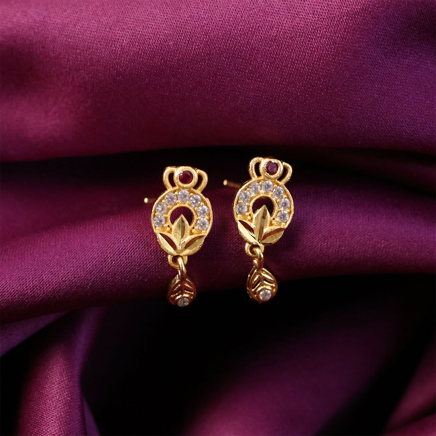 Close-up of gold floral earrings with ruby and white stones