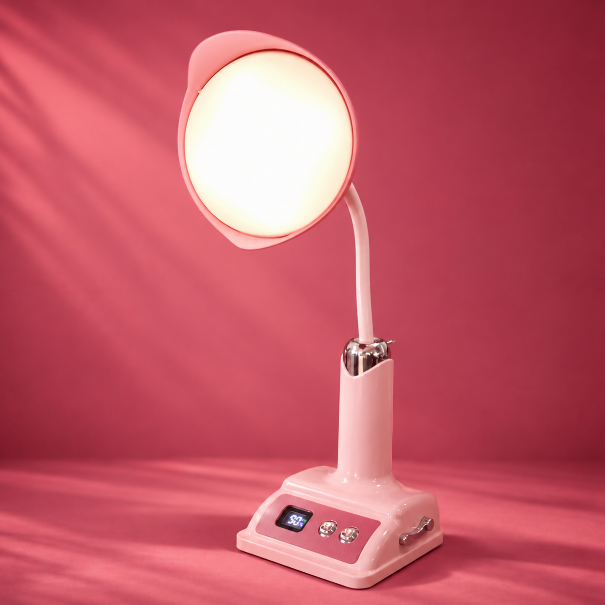 A pink desk lamp with a bright, round light and a digital display on its base stands against a solid pink background.