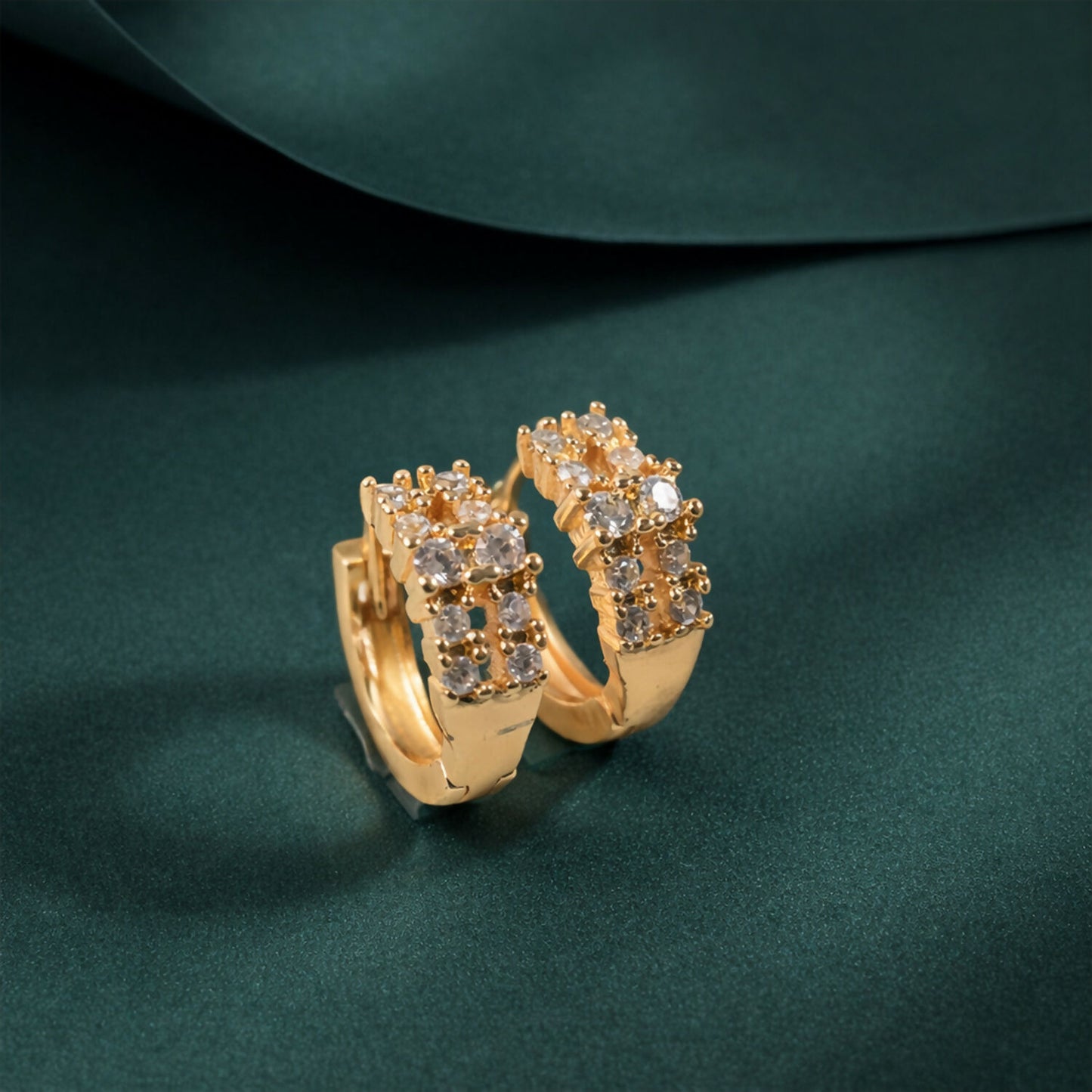 Close-up of gold-tone crystal hoop earrings with polished finish