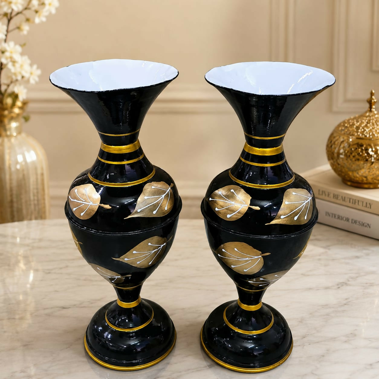 Two black metal flower pots with gold accents displayed together