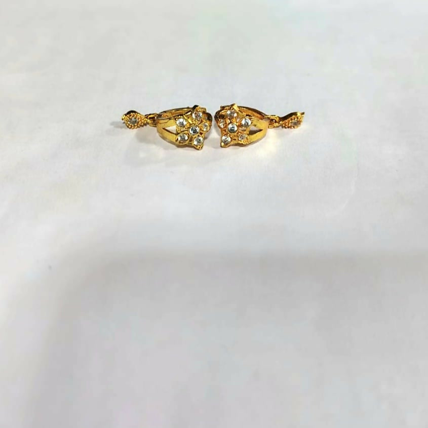 Front view of gold plated floral and star dangle huggie earrings showing detailed design