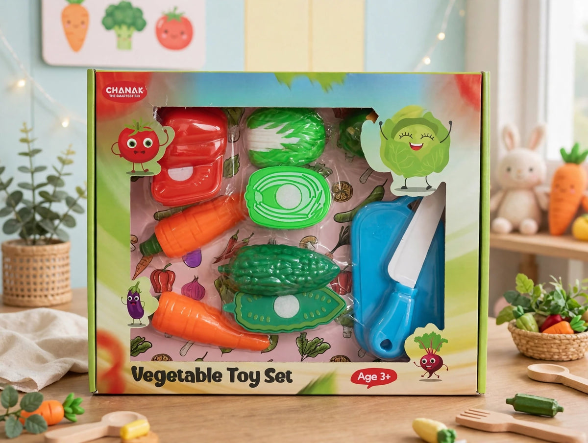 A green box containing a plastic vegetable toy set with a knife and chopping board is on a wooden table.