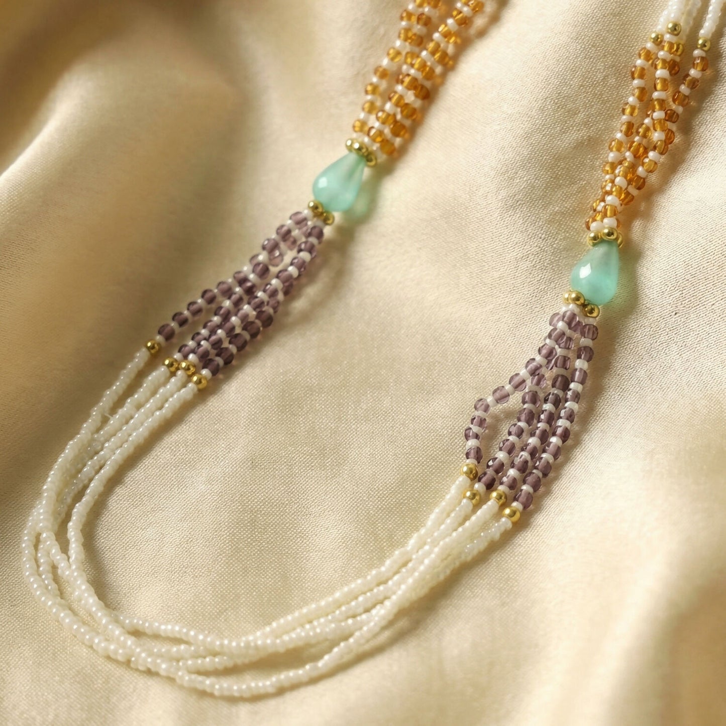 Side view of pearl necklace with green and lavender bead accents
