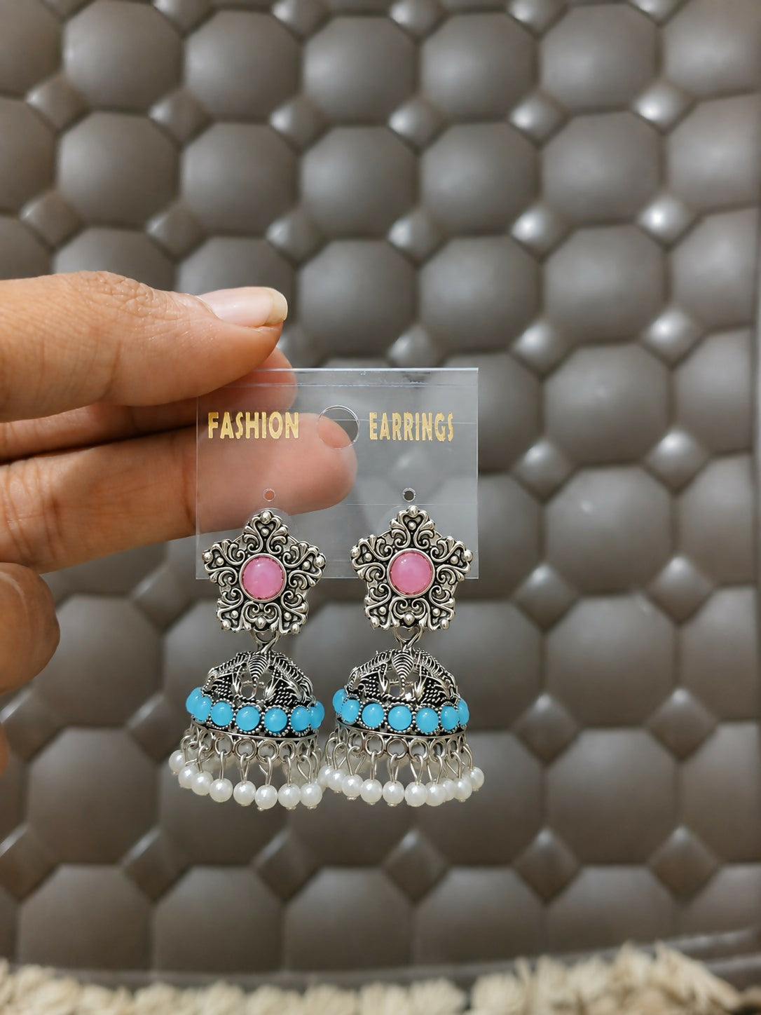 Model wearing oxidized silver jhumka earrings with pink stones and turquoise beads