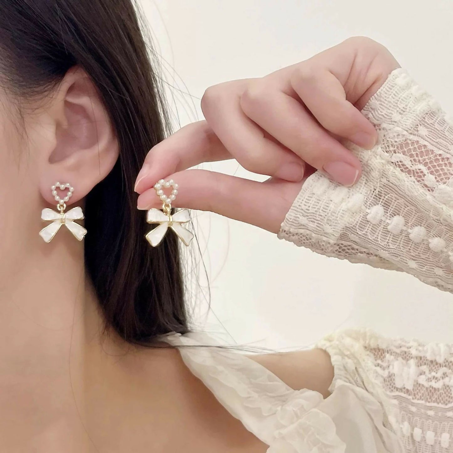 Close-up of pearl heart and bow earrings showing texture and gold accents