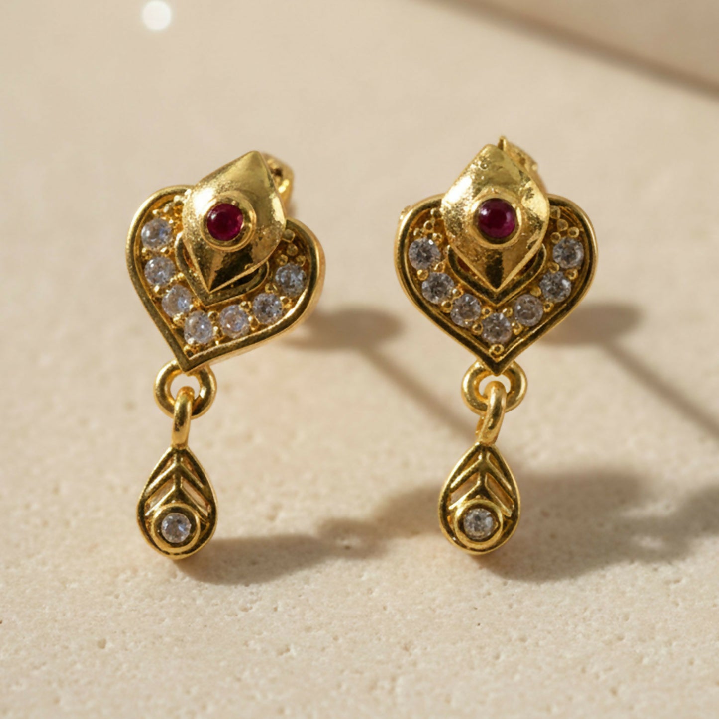 Close-up of Ruby and Crystal Heart Drop Earrings in gold