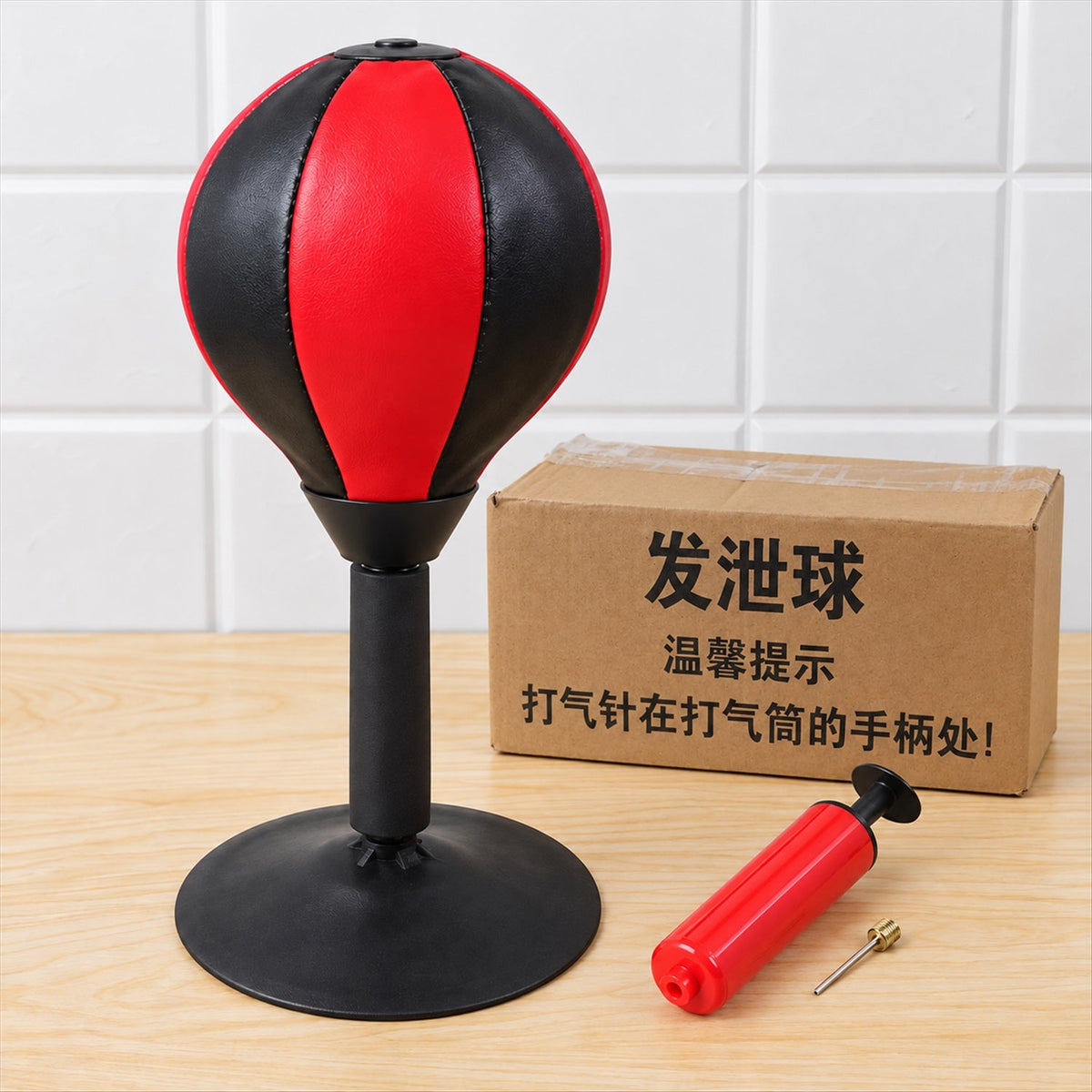 A red and black desktop punching ball with a pump and needle, next to a brown box with Chinese writing.
