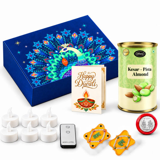 A vibrant blue box with a peacock design, a tin of Kesar-Pista almonds, a Diwali card, LED tealights, gold Shubh-Labh decor,
