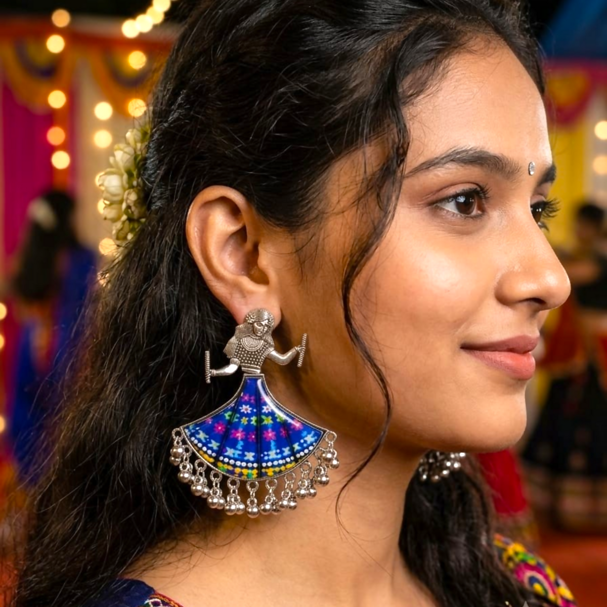 Woman wearing a single oxidized silver dancing doll earring with a blue floral skirt.