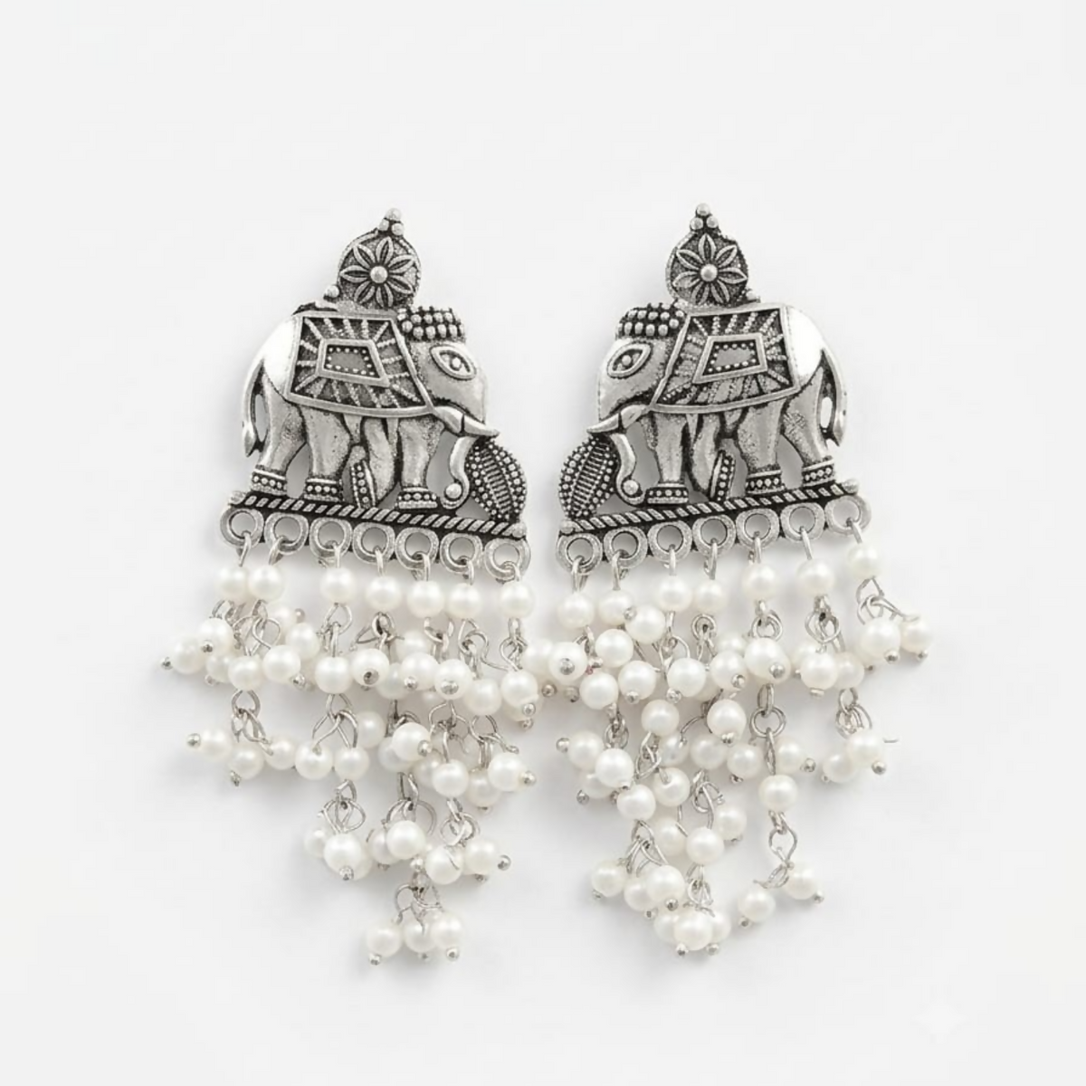 A pair of oxidized silver elephant earrings with white pearl drops on a plain white background.