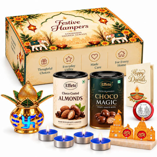 A festive hamper box with two chocolate tins, a golden kalash, four blue tealights, and Shubh-Labh decor.