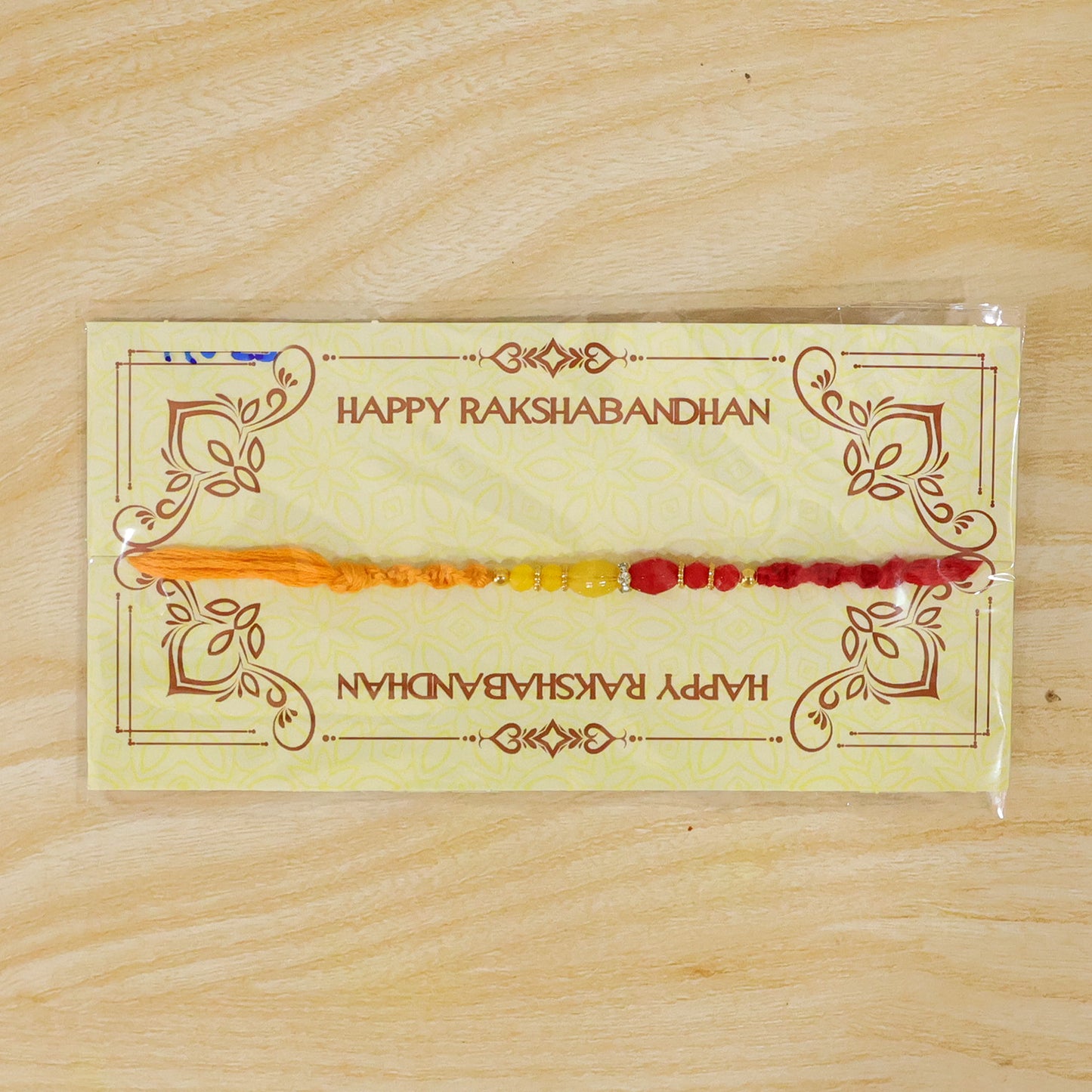 Red Thread Rakhi with Yellow and Orange Bead Pendant Accents