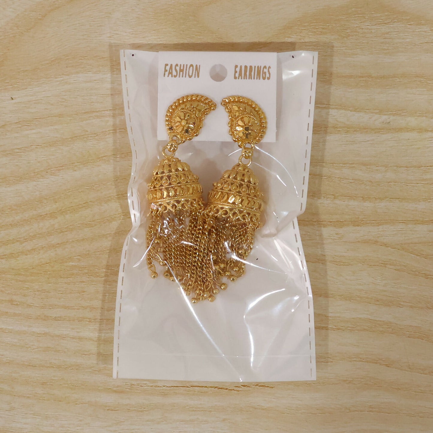 Gold-plated jhumka earrings displayed on neutral background
