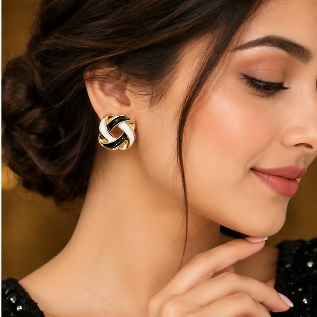 A woman models a black and white enamel knot stud earring on her earlobe.